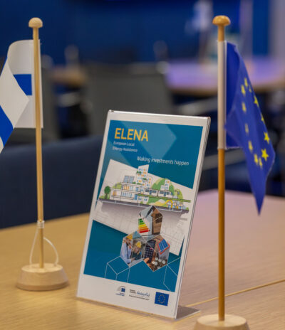 ELENA event table sign between the tiny flags of Finland and EU.